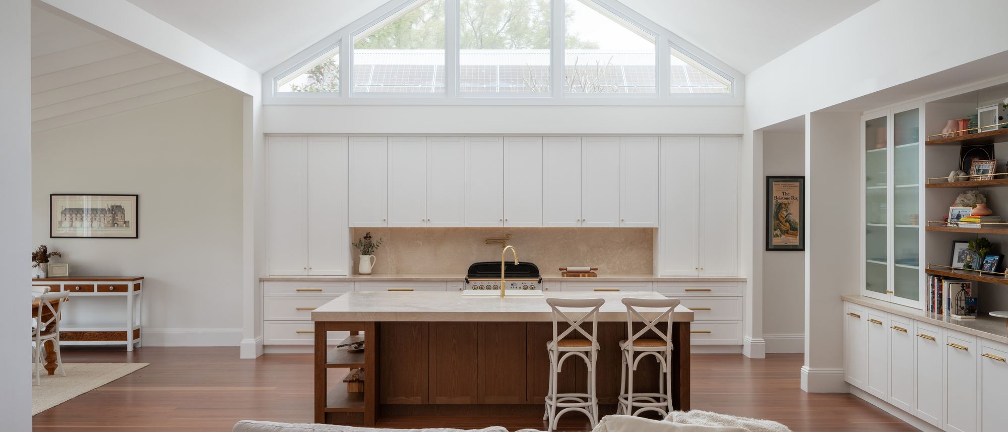 Cathedral-ceiling kitchen in Bolwarra with a timber island, cream stone top and a tall picture window