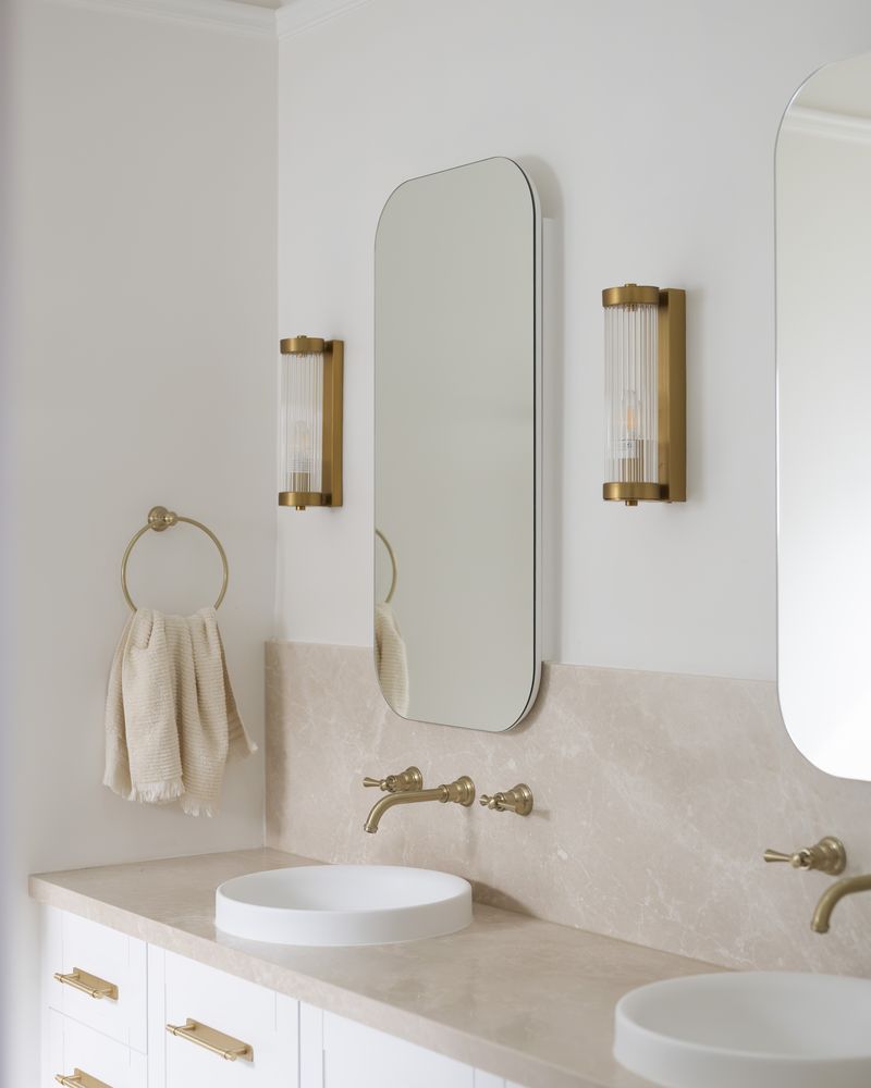 Double stone vanity with brass tapware and arched mirrors