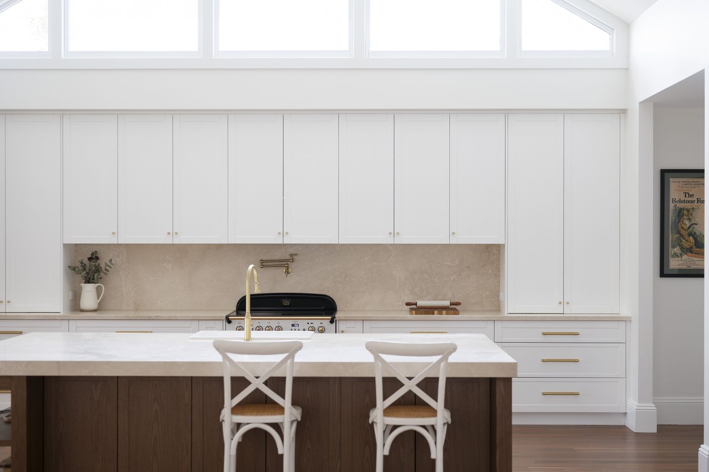 Stone island with cross-back stools in a white Bolwarra kitchen