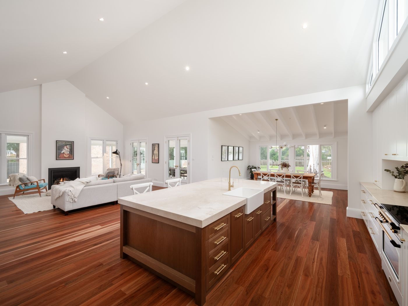Wide Hamptons kitchen in Bolwarra with a timber island, farmhouse sink and cream stone benchtops